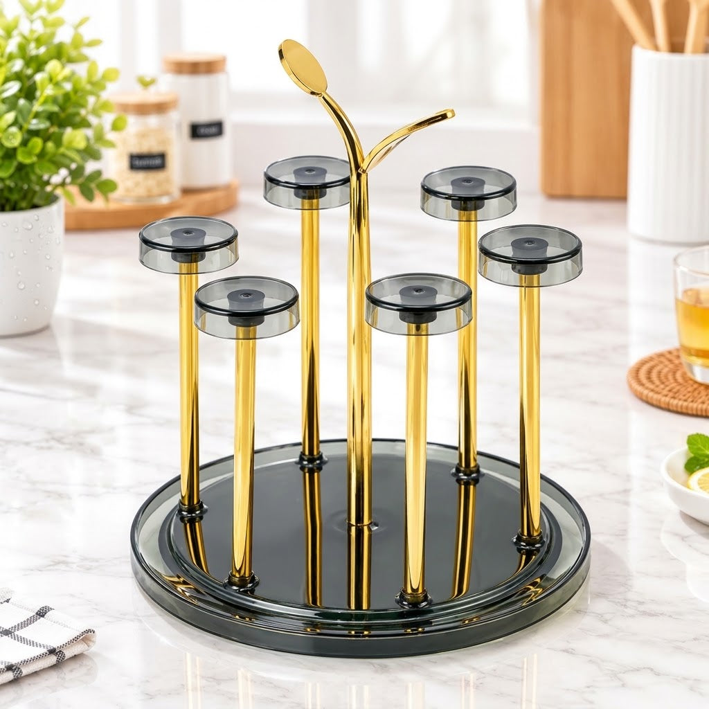 A gold and black glass tea or candle holder set on a marble countertop, featuring a round black base, five gold candlesticks with dark gray translucent tops, and a central gold spoon-shaped stem.