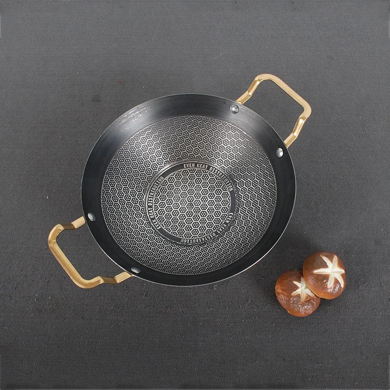 Black frying pan with gold handles on a dark gray background